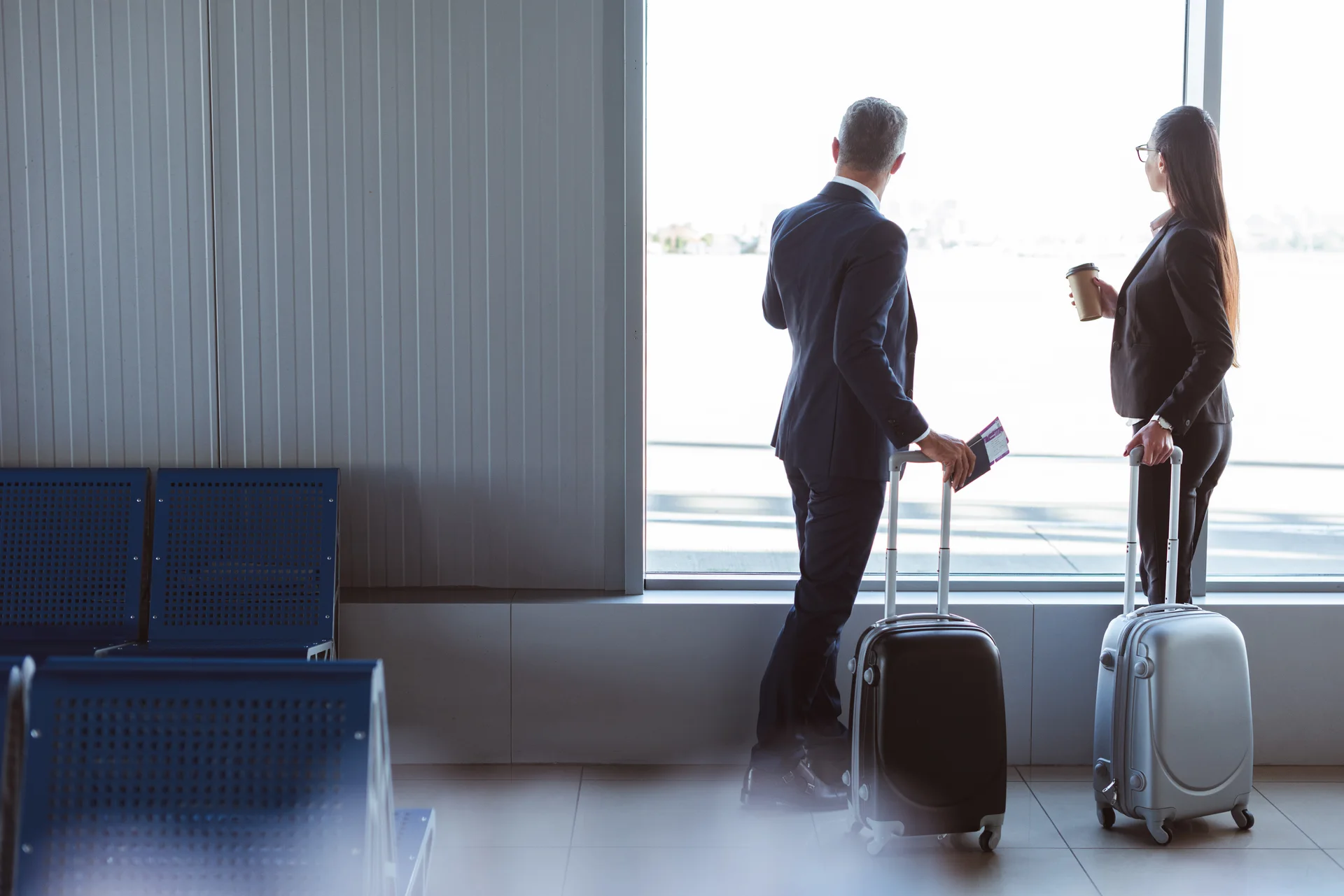 Executivos com malas observando a pista de um aeroporto